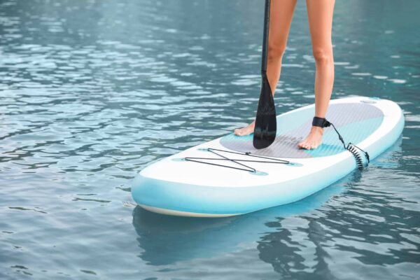 Young woman using paddle board for sup surfing in river